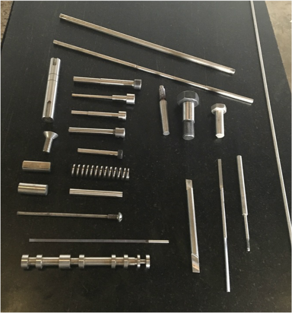 Image of several types of dowel pins, bolts, cotter pins on table 